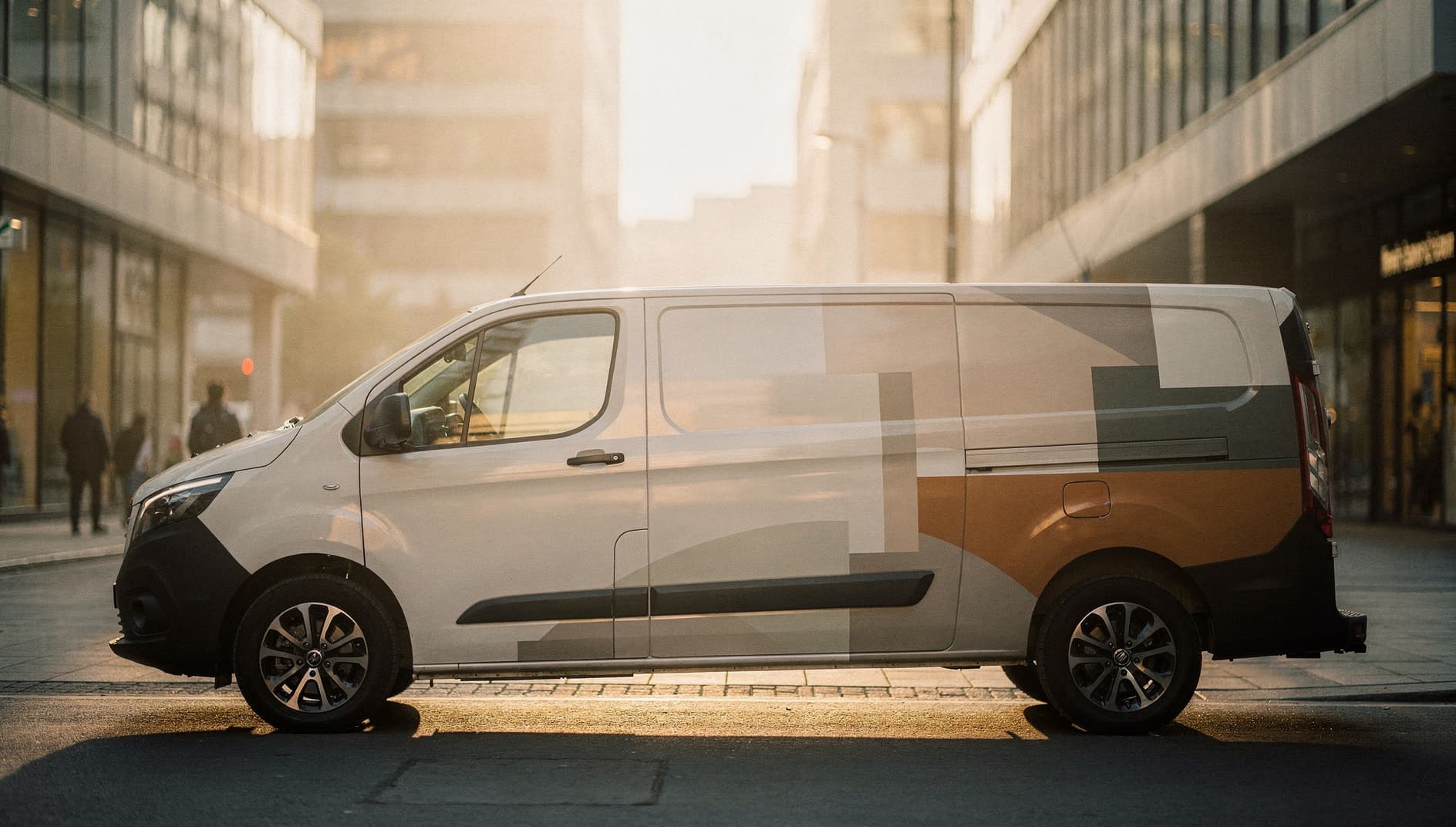 Wrapped delivery van on a city street at golden-hour sunrise